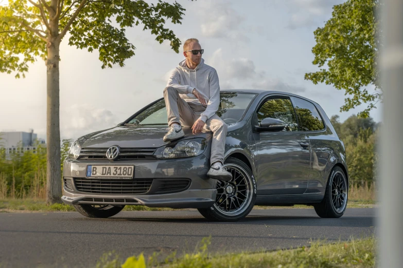 man sitting on the hood of a sports car