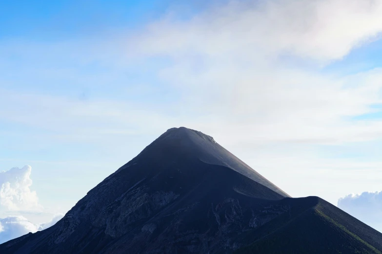 a tall mountain with clouds in the sky