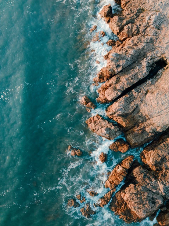 a wave crashes on the rock ledge above