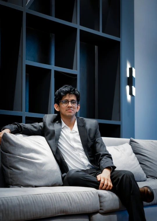 a man in glasses sitting on a couch in a room