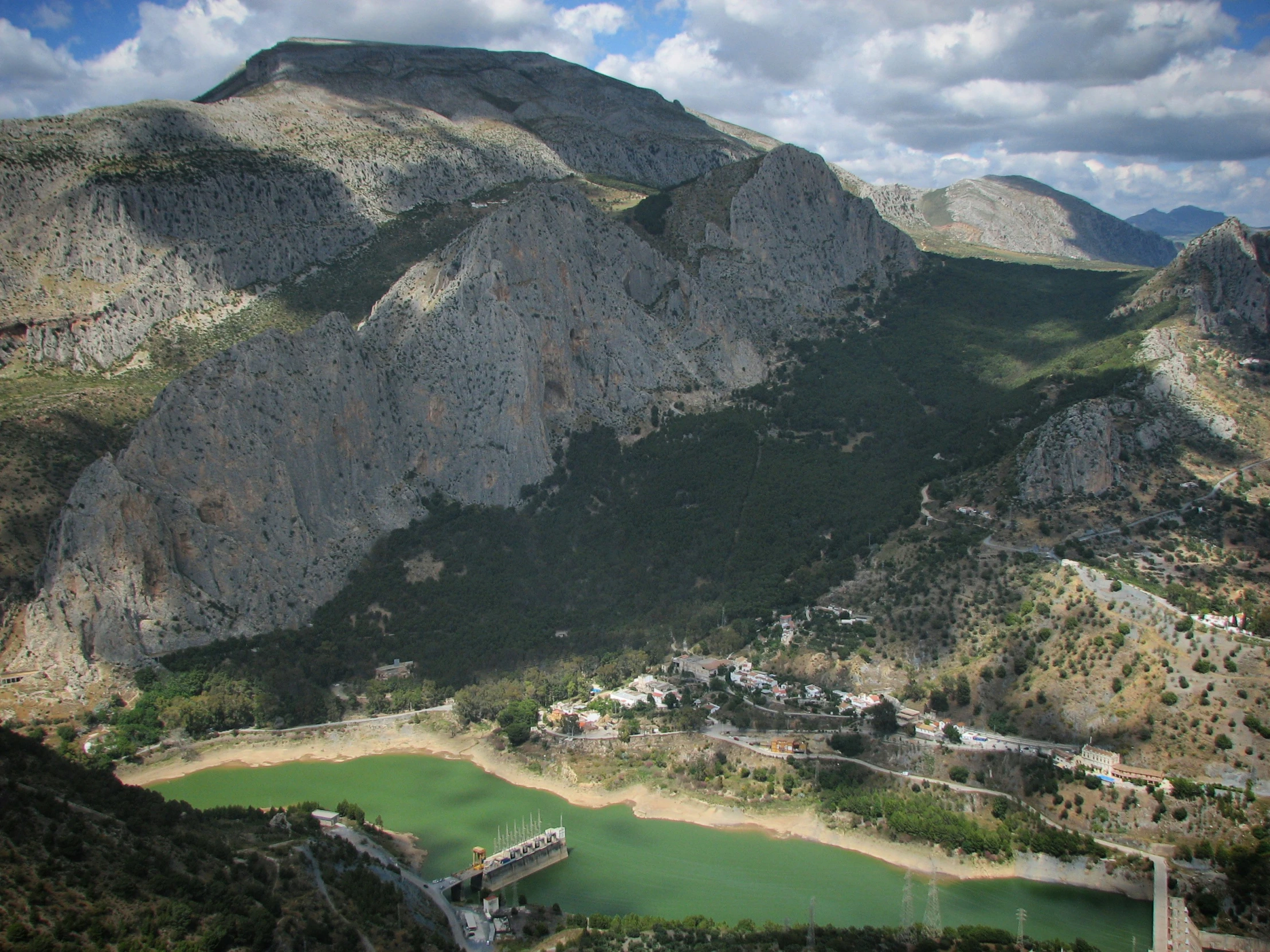 an aerial view shows a mountain, lake, and road