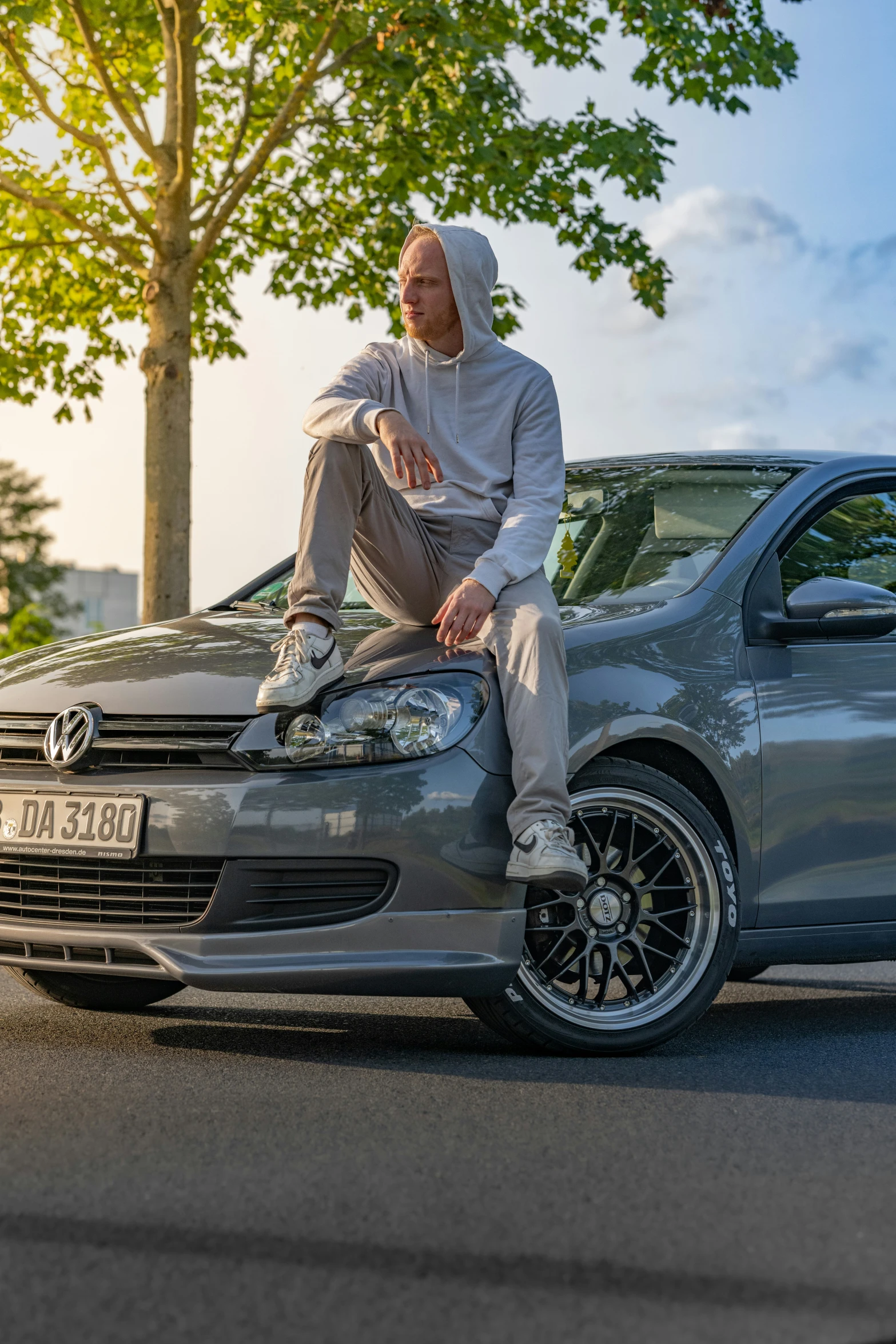 the man is sitting on the hood of his car