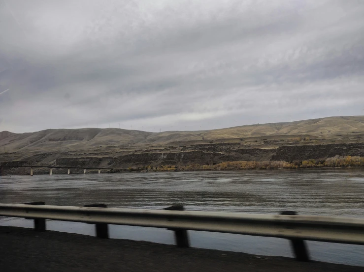 a river is flowing over land with a bridge in the distance