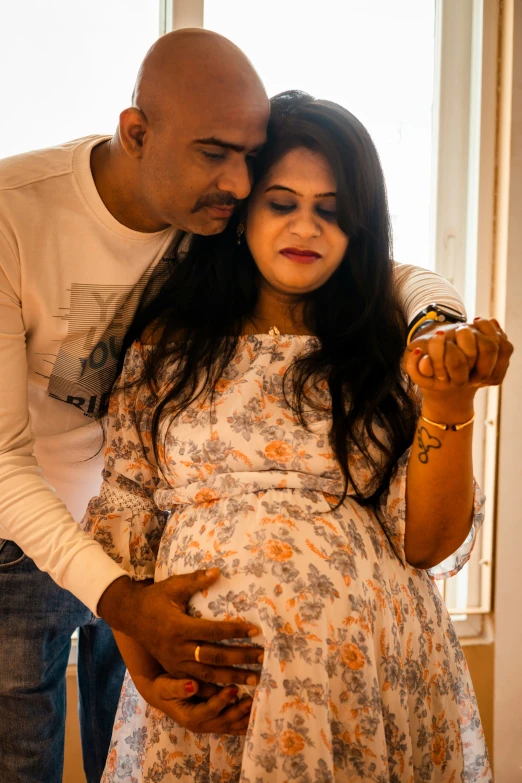man kisses the forehead of pregnant woman holding her hand in her hand