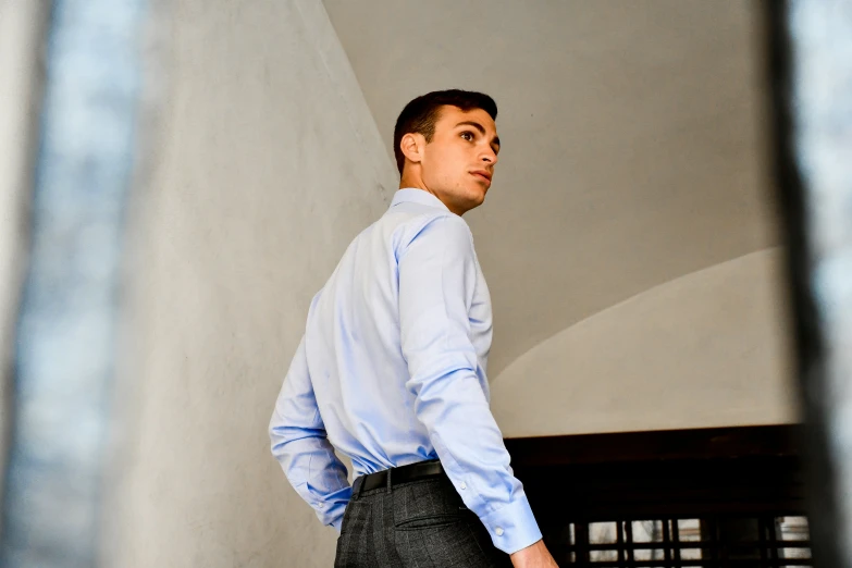 young man in dress shirt and slacks standing outside window