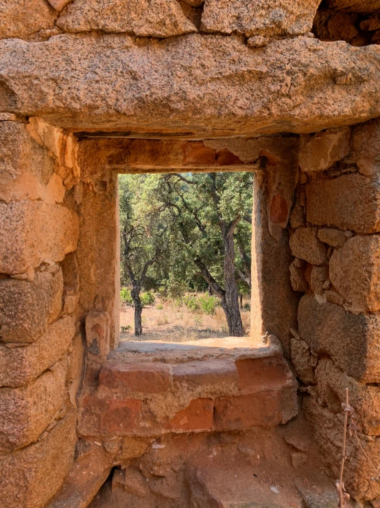 a window inside a rock structure with trees in the background