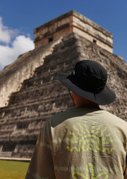 a boy wearing a black hat and jacket near a pyramid