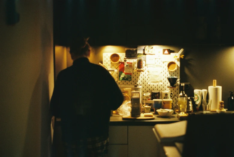 a man at the counter making a drink in the dark