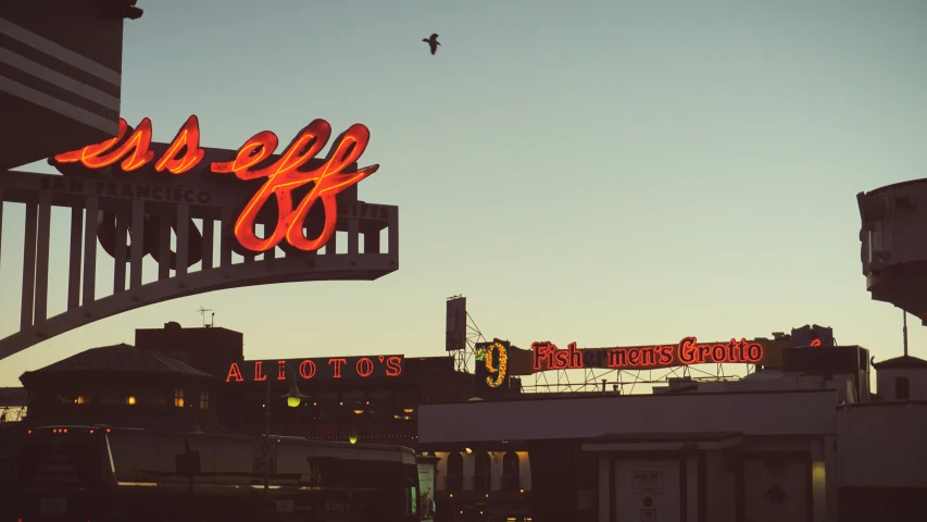 a view of an outdoor shopping area with a neon sign over the top