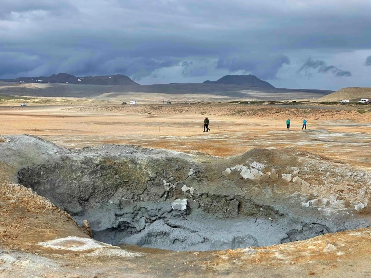 three people walking through an open, barren terrain