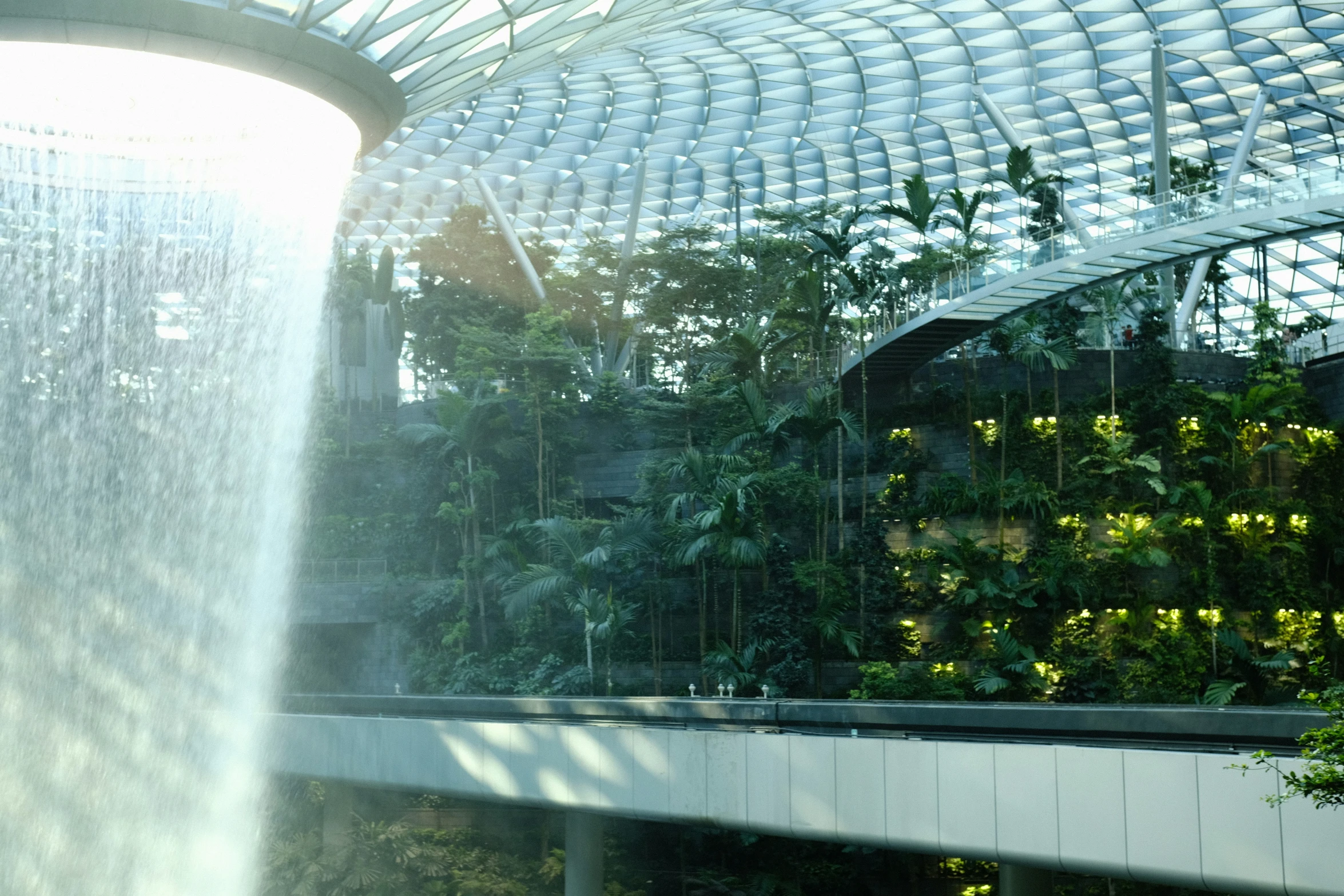 a building with plants in the middle and a waterfall at the front