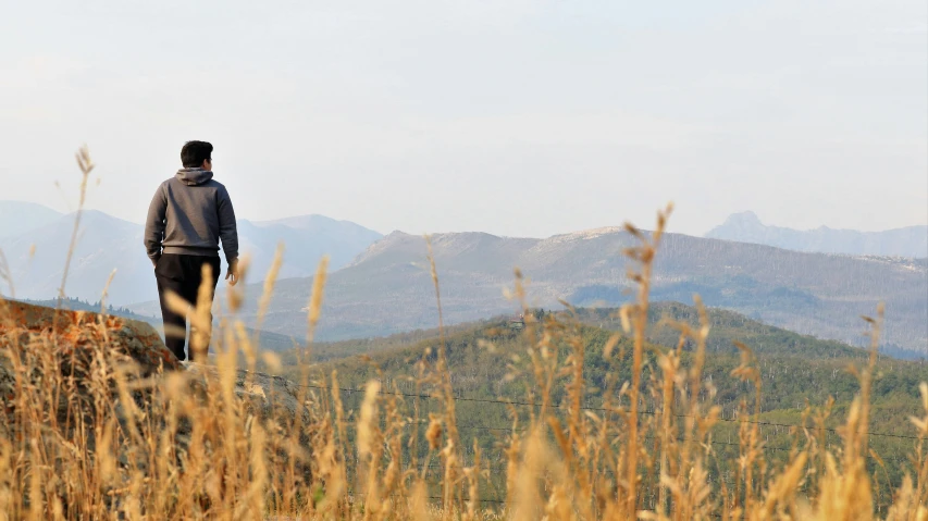 a man looks into the distance over the mountains