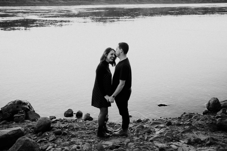 man kissing woman near the water at sunrise