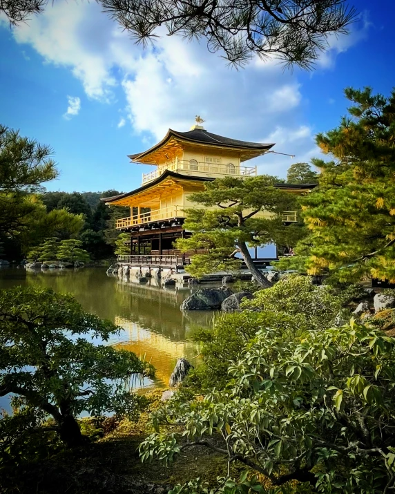 a pagoda tower stands above a body of water surrounded by green trees