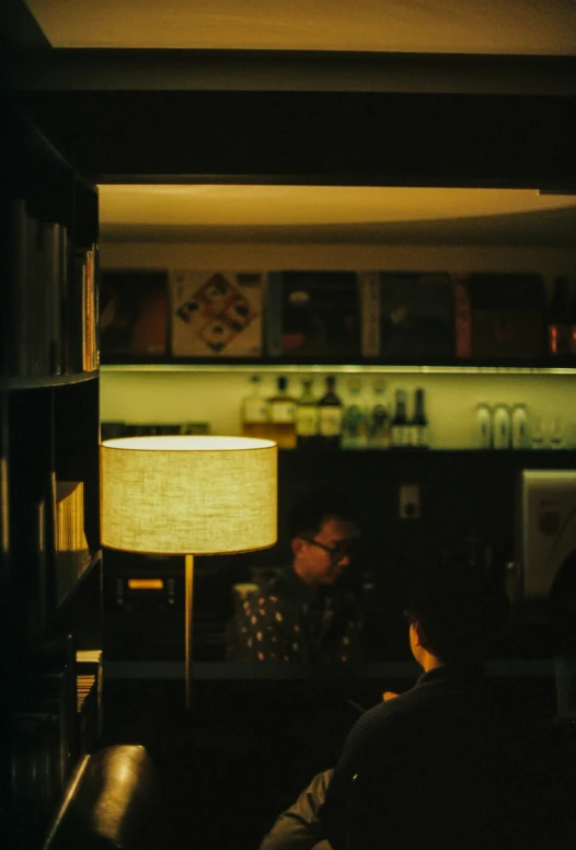 a man sitting in front of a lamp in a dimly lit room