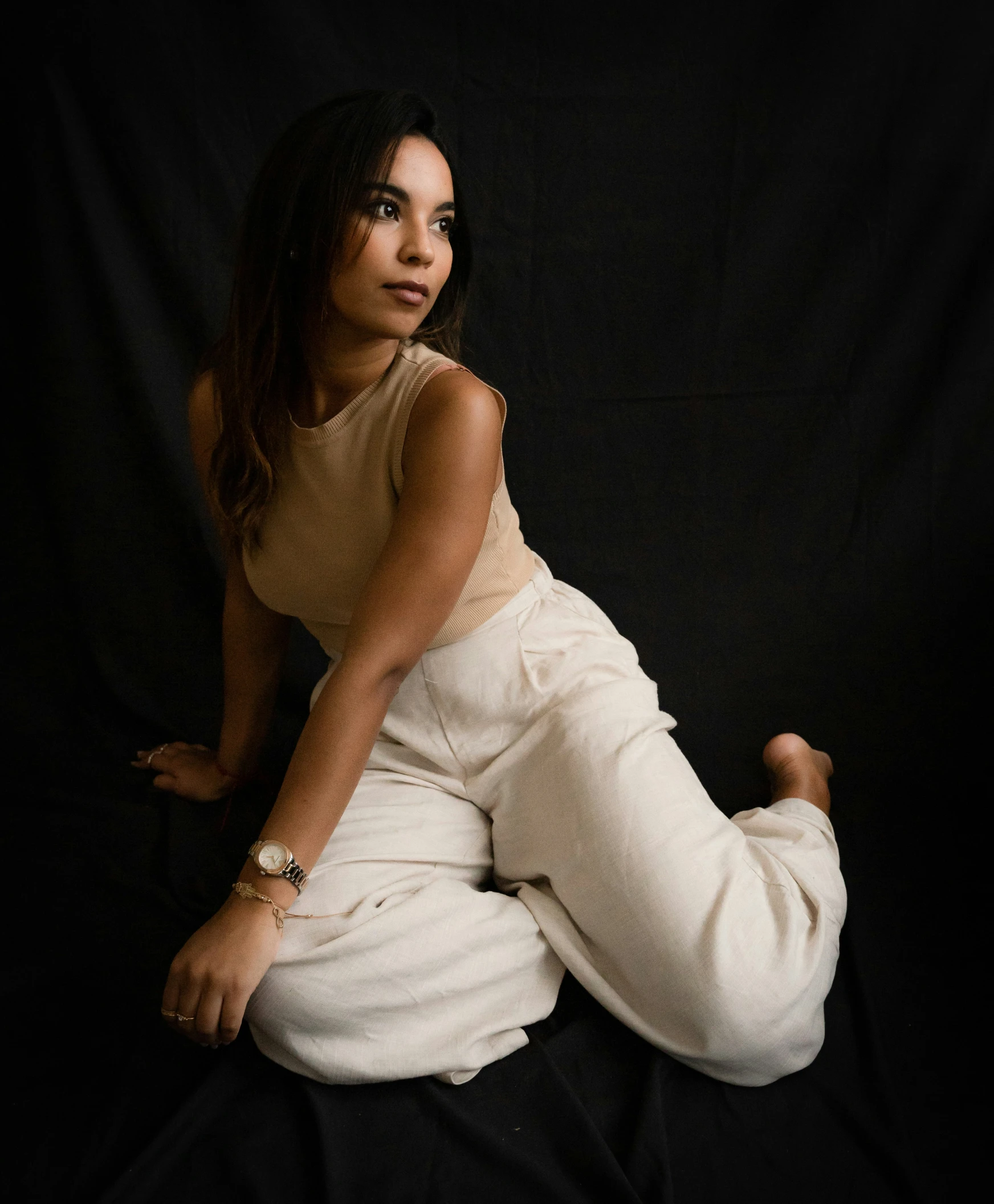 a young woman in white sits on black with her legs stretched out