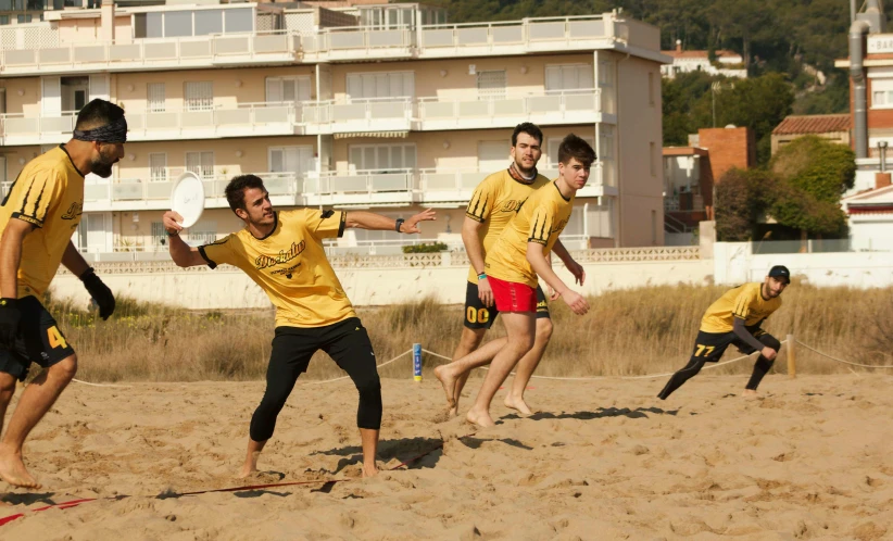 a group of men are playing frisbee in the sand