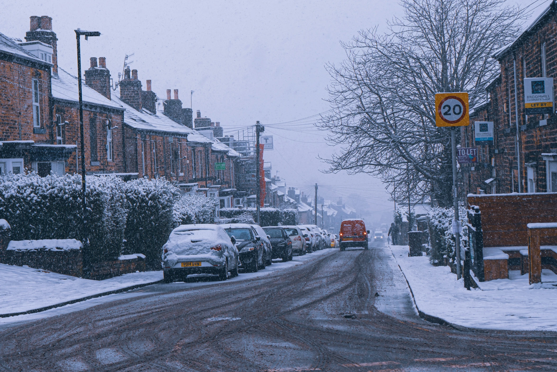 cars parked along a snowy street next to brown buildings