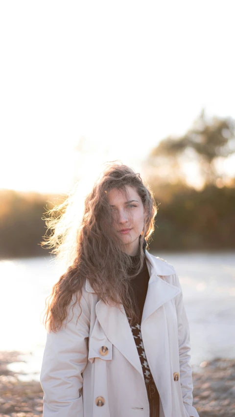 a woman standing on a beach with her hair blowing in the wind