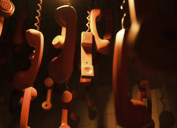 telephones hanging in line against a wall of different colors