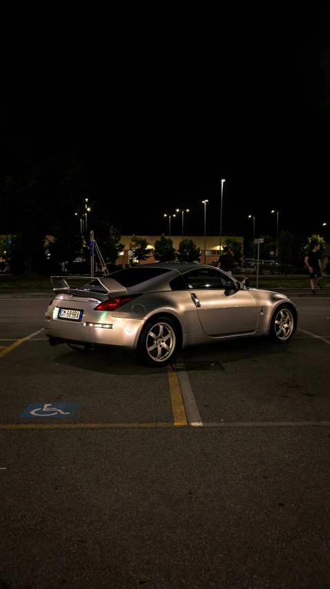 a silver sports car parked in a parking lot at night