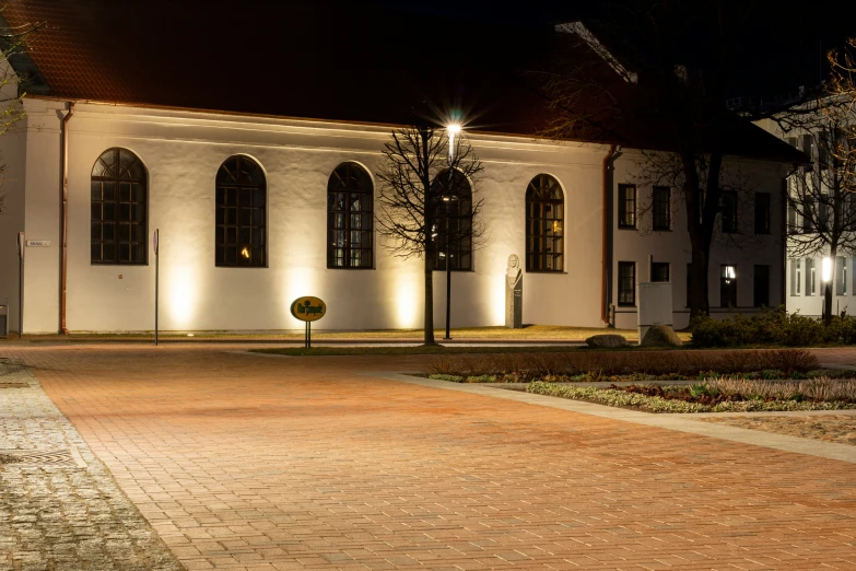 an elegant house at night with lights on the side and landscaping