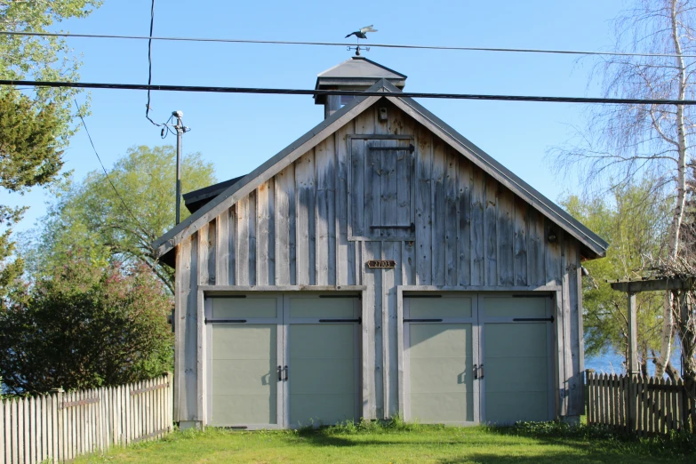 an old wooden shed has two garages, one with the doors open