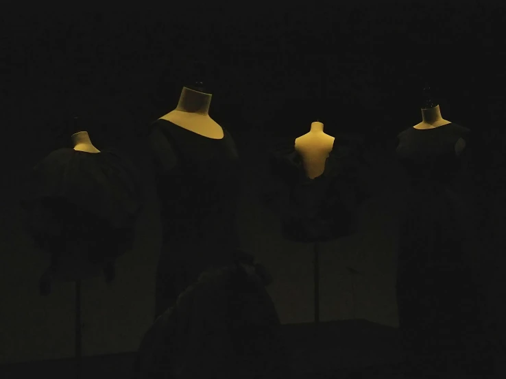 mannequins in the dark wearing dresses and lamps