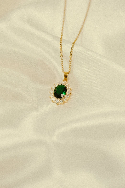 a gold and green necklace on top of sand