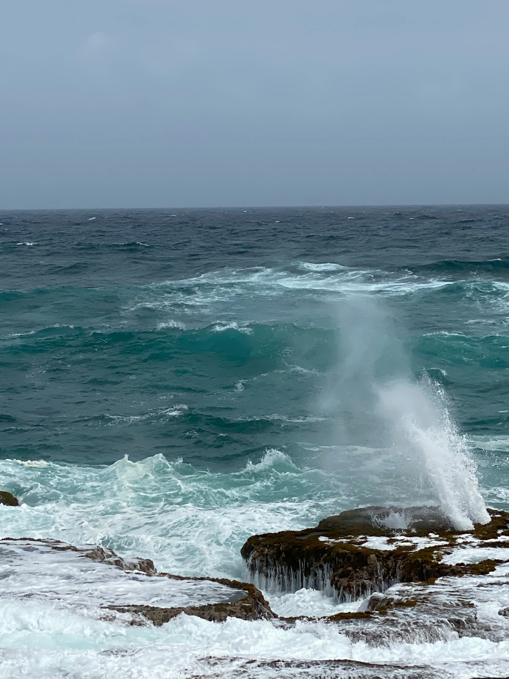 waves splash in the ocean off of the rocks