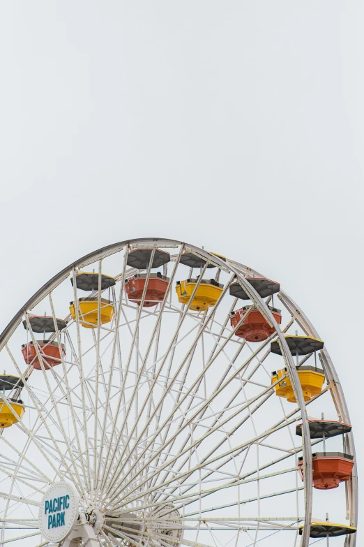 a ferris wheel filled with yellow cars on top of a beach