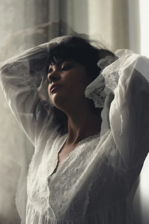 a woman in a white dress stands next to a wall