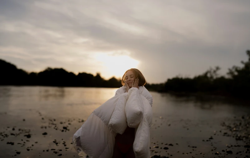 a woman on the beach dressed in winter attire and holding her hands to her mouth