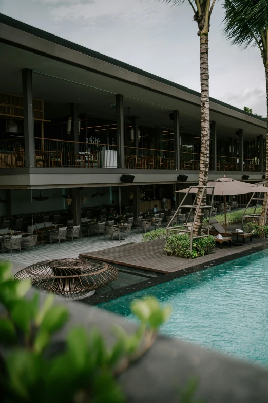 a long pool with lounge chairs around it near a building