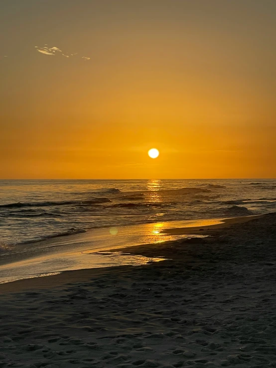 a large orange sun is shining above the ocean