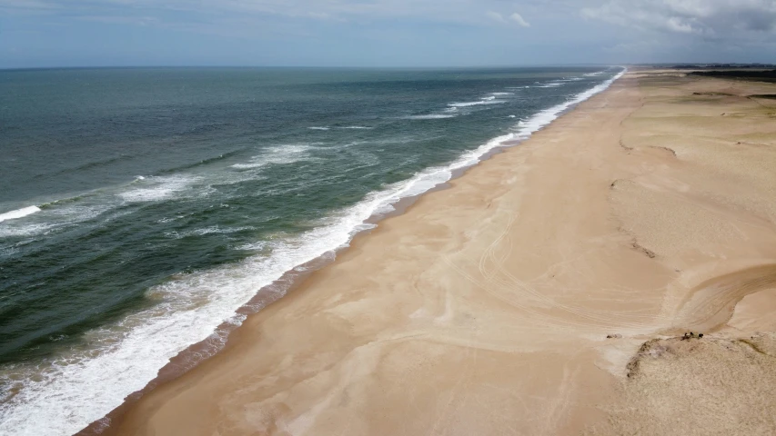 the ocean is crashing over a wide beach