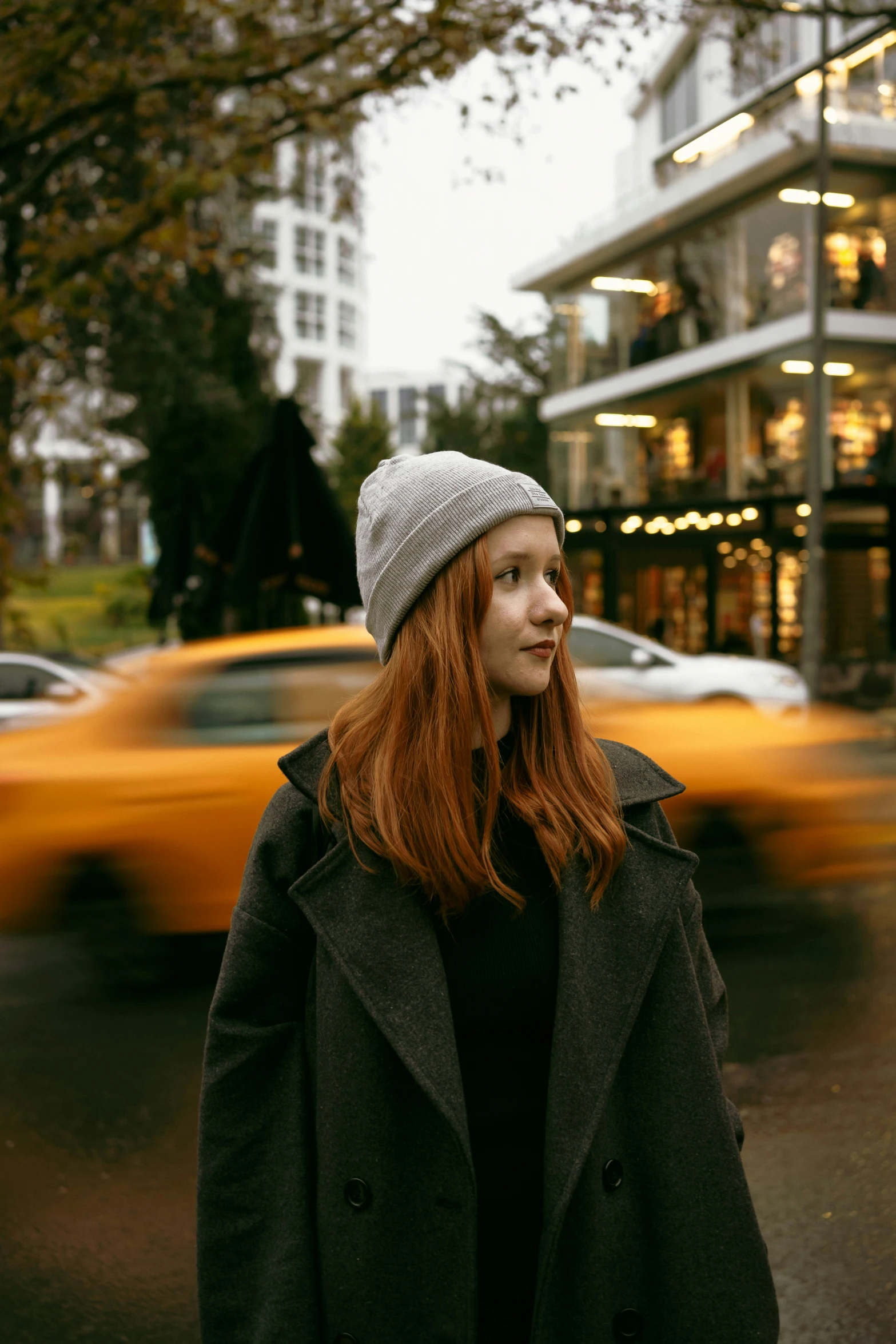 a lady with red hair standing in the street