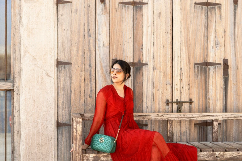 a woman in a red dress sitting on a wooden bench