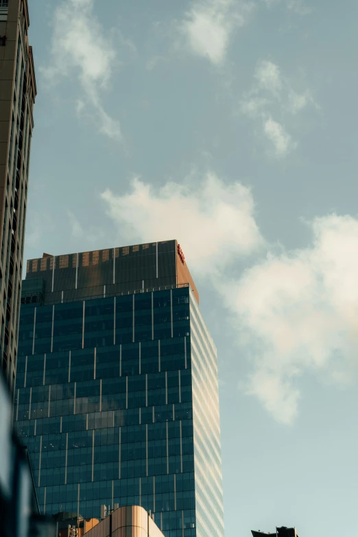 a city skyline with the sky and clouds reflected in skyscr windows