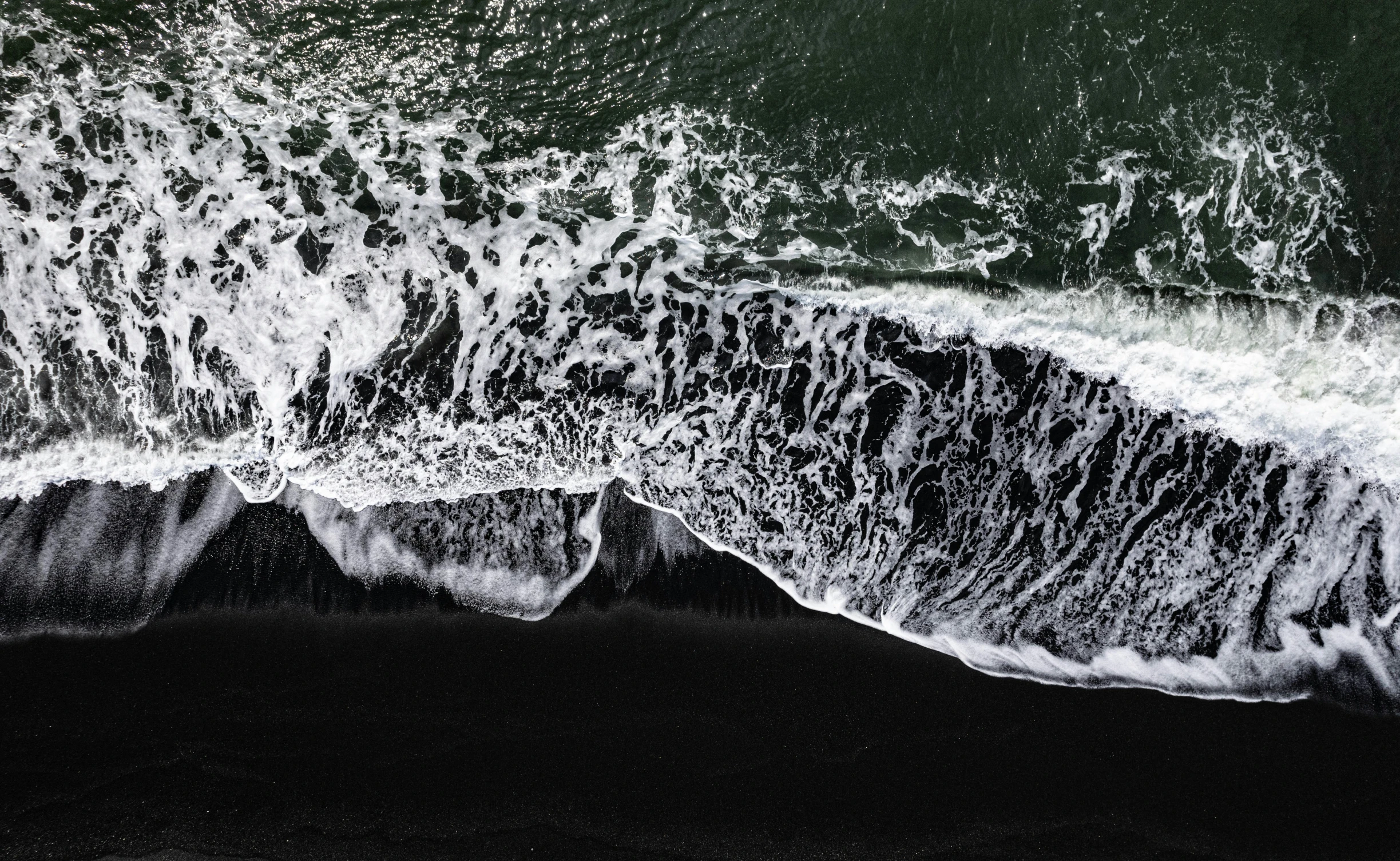 an aerial view of waves crashing on the beach