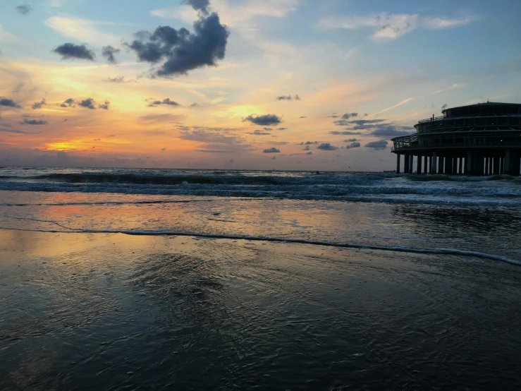 a beach at sunset with a wooden pier in the distance