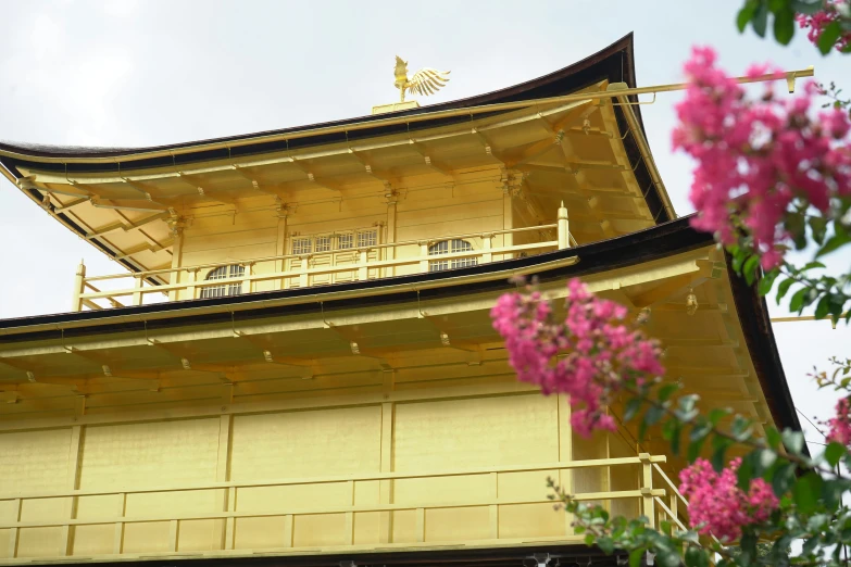 an oriental structure with yellow paint and some purple flowers