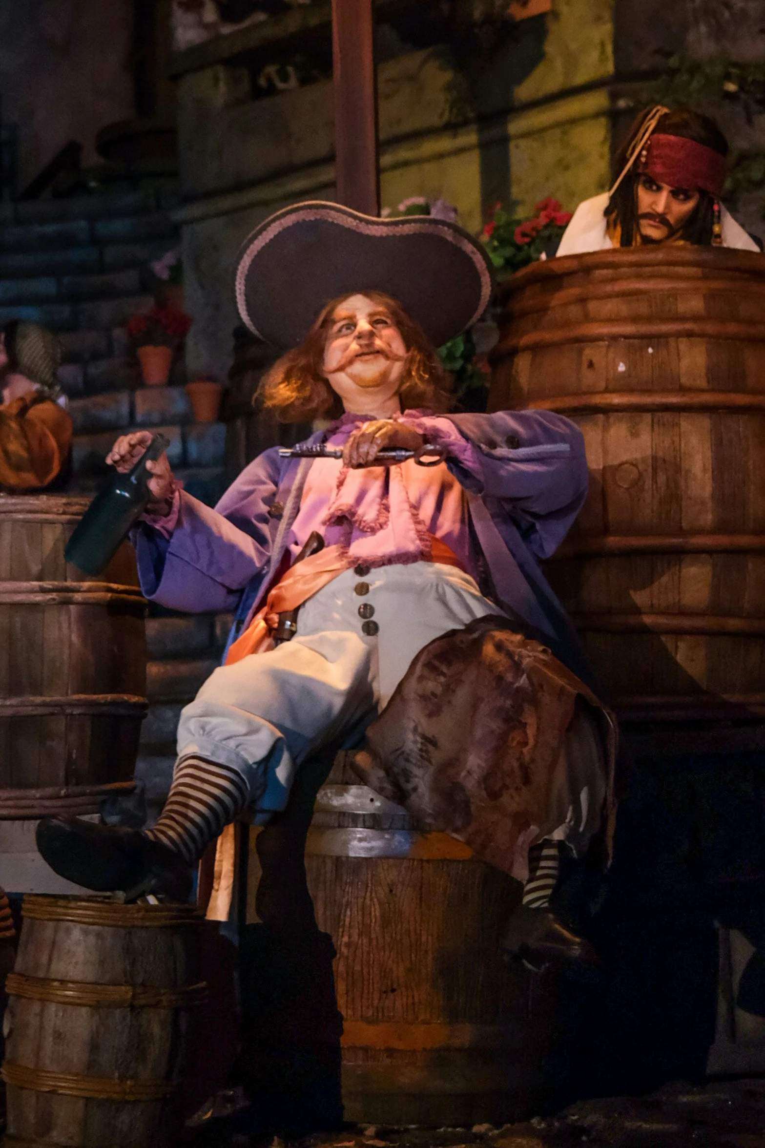 a man wearing an old fashioned pirate outfit sitting on a barrel