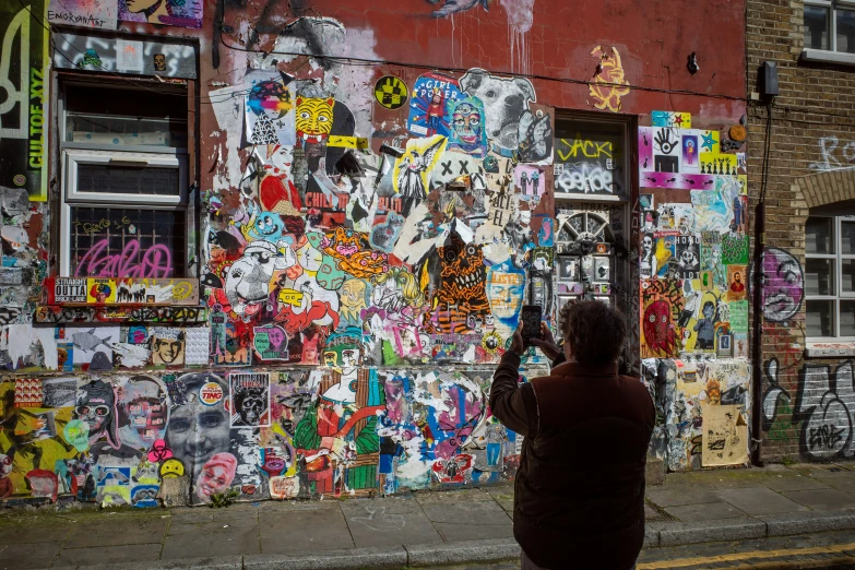 a woman taking pictures of a building with a lot of graffiti on it
