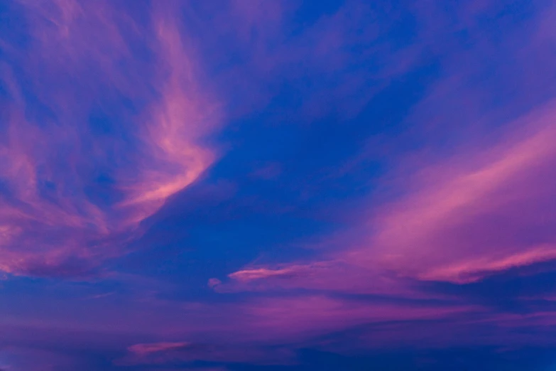 a large jetliner flying through a purple cloudy sky