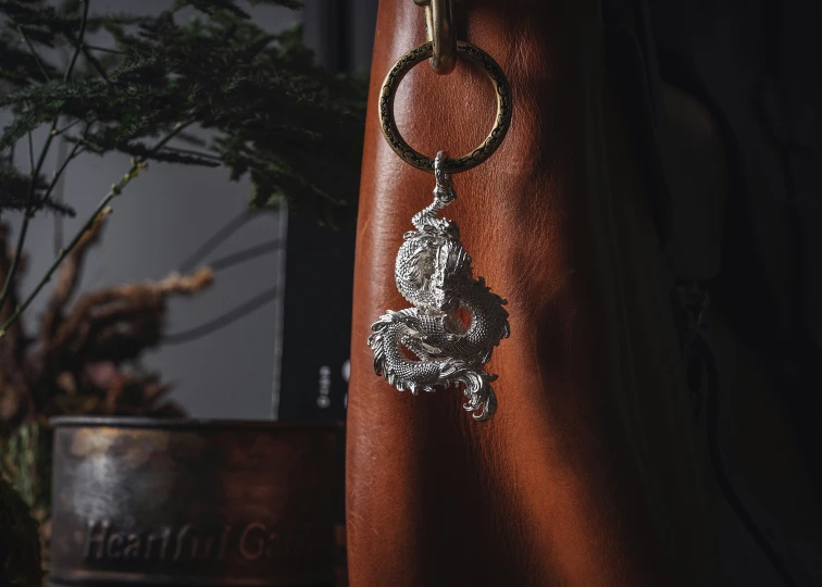 a silver keychain hanging from a leather case