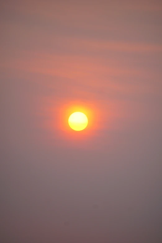 an airplane flying through a smoggy sky at sunset