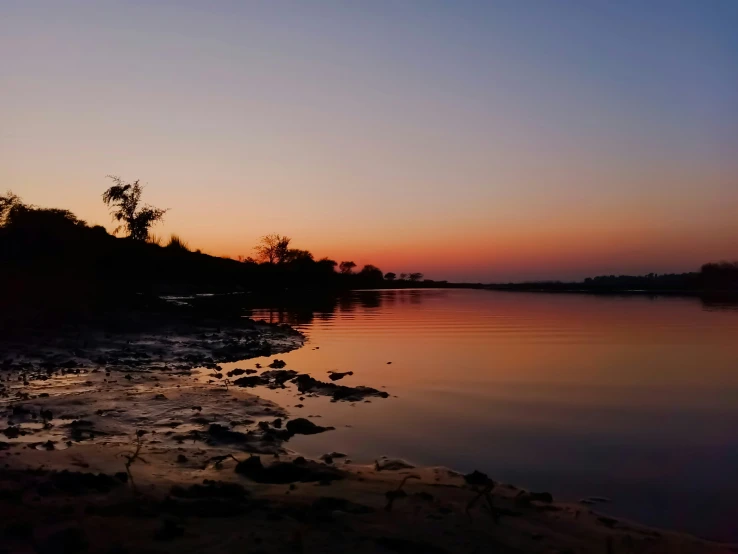 a sunset with water and rocks in the foreground