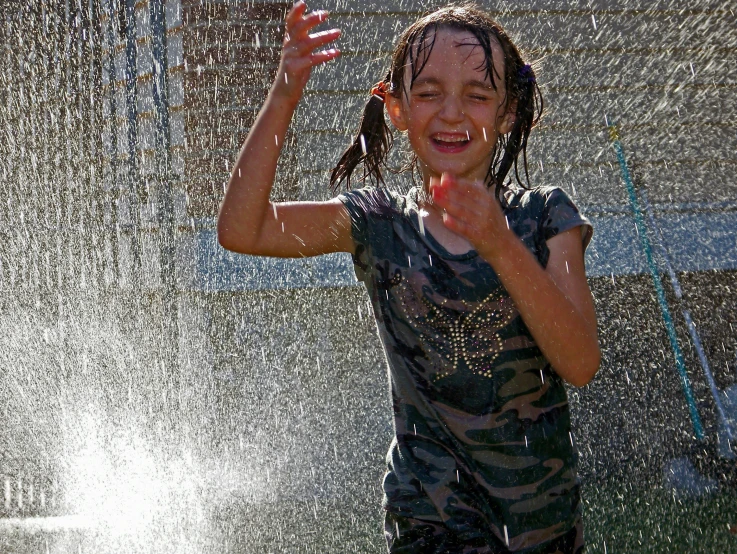 little girl in bathing suit playing in the sprinkles