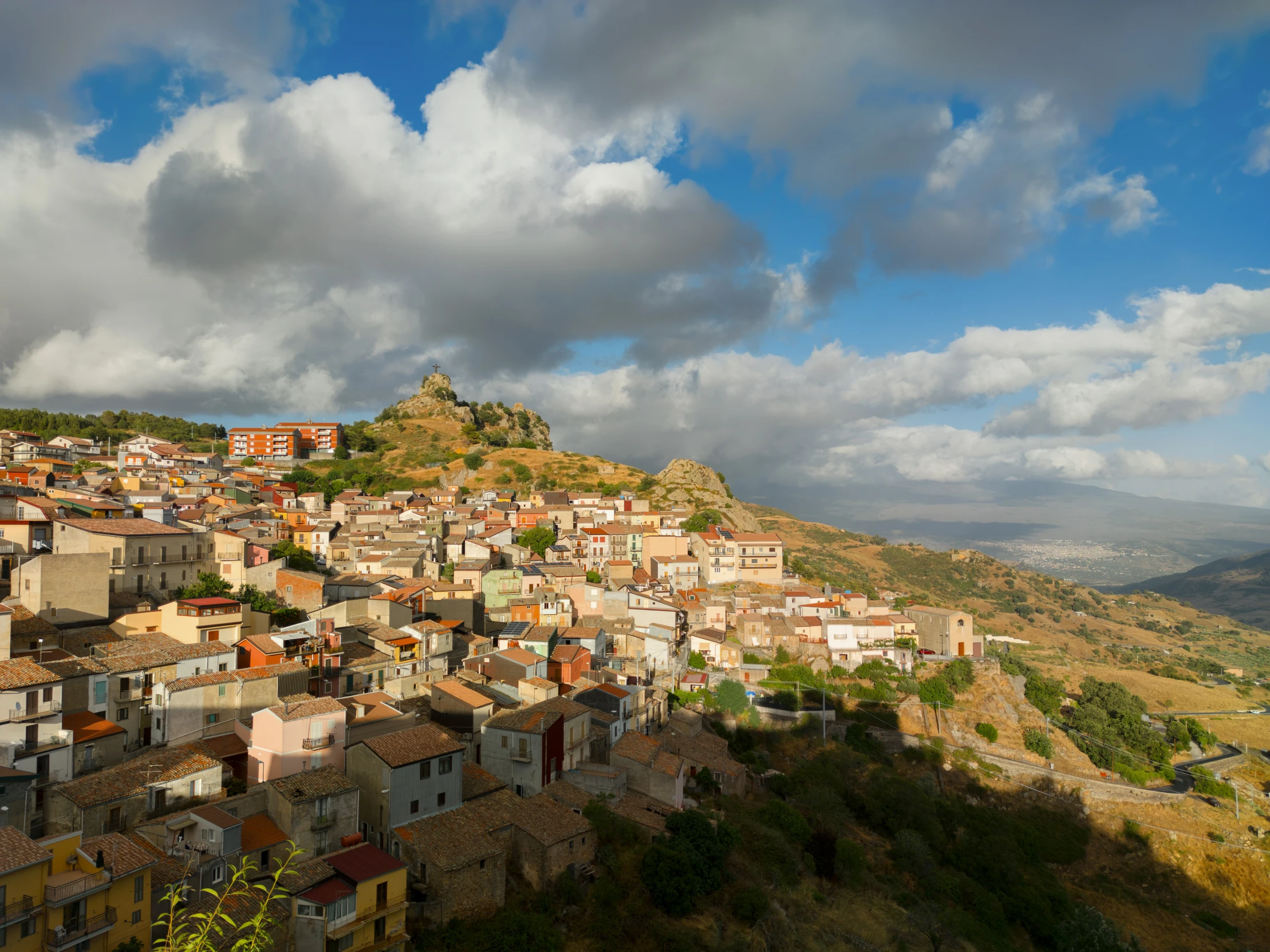 the town on top of a hill with a cloudy sky